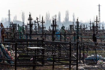 Fototapeta premium A wide shot of an old, crowded Orthodox Christianity cemetery with numerous black metal crosses and fences under a hazy sky.