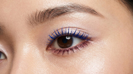 Obraz premium Close-up of eye with vivid blue mascara on upper lashes, fashion beauty photo.