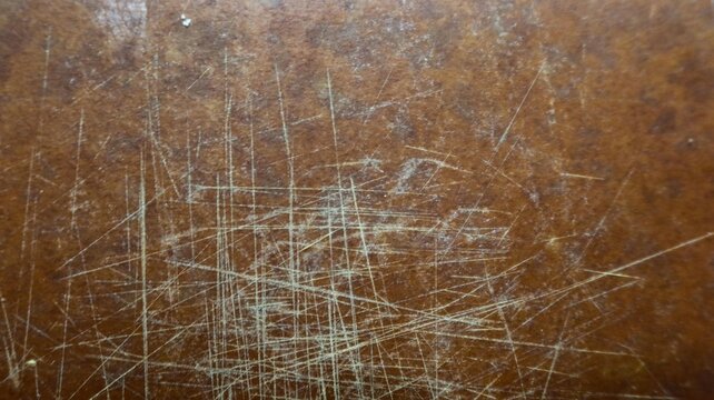 Close-up of scratched wooden surface with intersecting marks revealing lighter tones beneath &ndash; textured background symbolizing wear, age, and durability