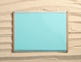 Fototapeta premium a single weathered blue ceramic tile resting on smooth golden sand under soft natural light