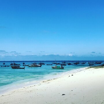 Traditional Fishing boats moored in the shallows by a sandy beach, Nungwi, Zanzibar, Tanzania