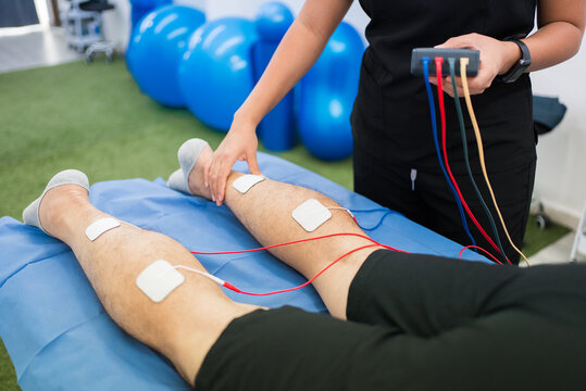 Physiotherapist performing electrostimulation therapy on patient's leg