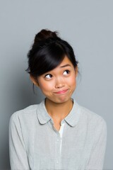 Fototapeta premium Young asian female adult pondering expression looking up thoughtful uncertain gray background