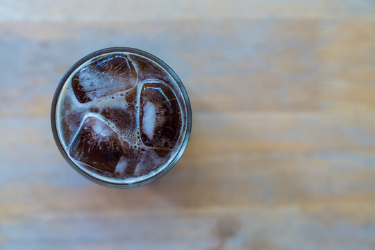 Cold iced americano coffee in glass on wood table, top view