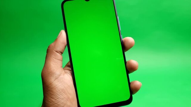 Person holding mobile phone with green screen for chroma key compositing