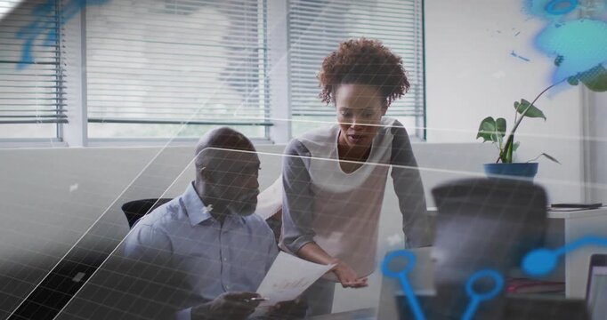 Woman pointing paper and guiding seated man to laptop, colleagues consulting to finalize report