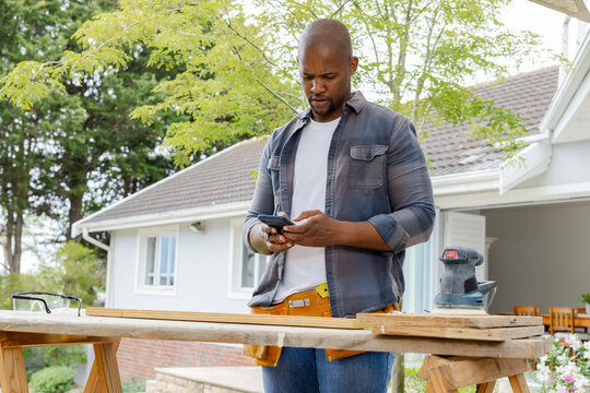 Carpenter pausing work and checking phone plans for cut accuracy animated marks showing over planks