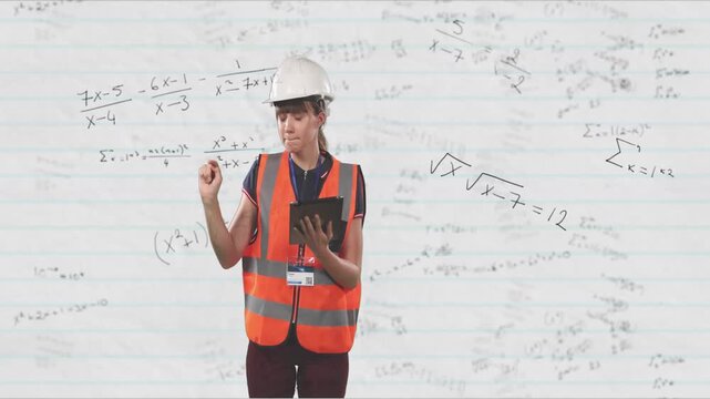 Female engineer holding tablet, tapping and pointing at lined board with formulas for checking work