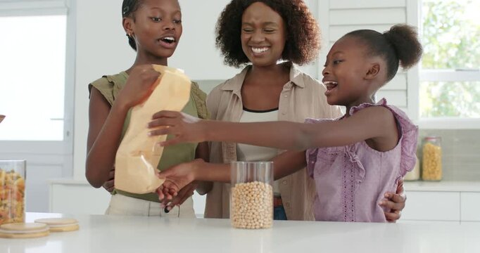 African American family lifting brown bag pouring snack pieces into glass jar for storage, hugging