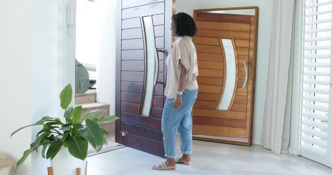 Vertical video: Girls exiting mother in beige top moving opening foyer door checking car backpacks