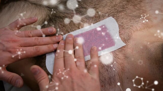 Client at spa, esthetician pressing wax strip, peeling for chest hair removal, particles over chest