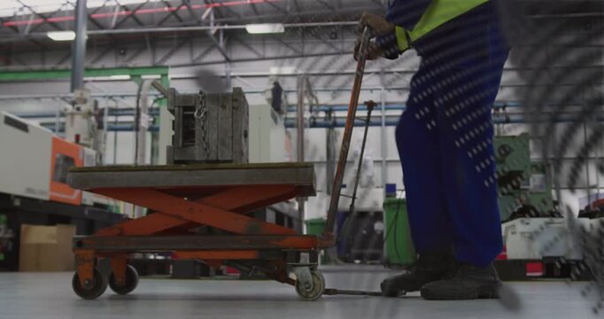 Factory worker pumping lever, guiding scissor-lift cart to lift and position heavy block under mesh