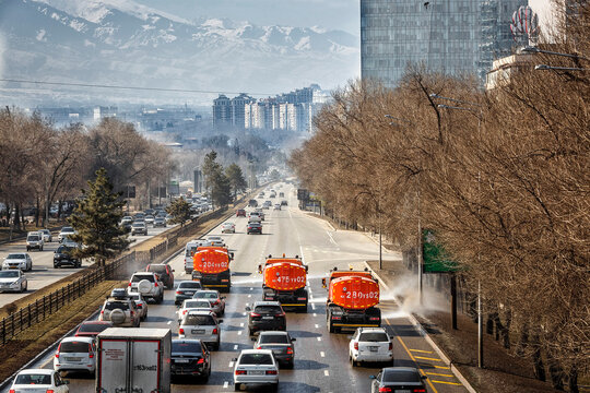 Almaty, Kazakhstan, March 2026: Municipal street cleaning vehicle washing and watering road at Al-Farabi Avenue against the backdrop of high-rise buildings