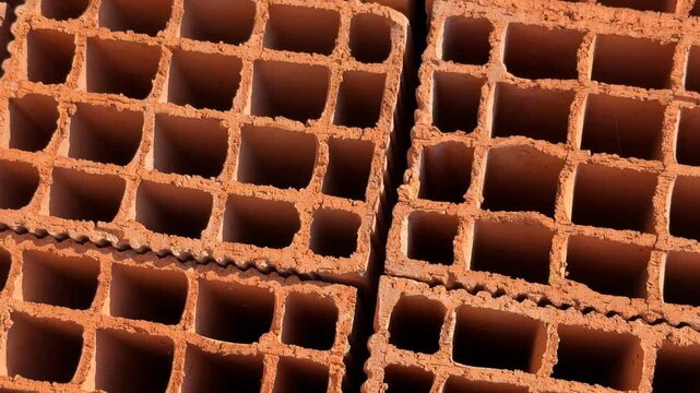 Stacked clay bricks showing rectangular hollow patterns, ideal for construction background