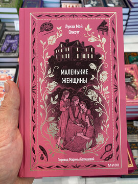 Moscow, Russia - March 15, 2026: Book cover of by Louisa May Alcott, featuring illustrations of four girls and a house design