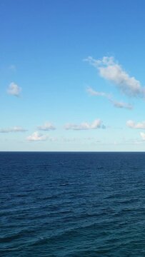 Wide view of a tranquil sea under a clear blue sky with scattered clouds, captured near Brindisi, Italy. Perfect for concepts of serenity, travel, and nature.