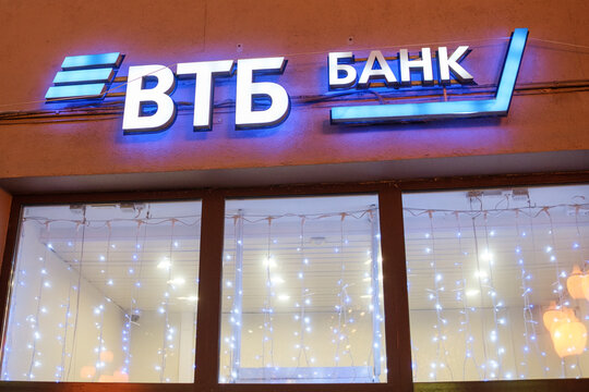 Moscow, Russia - February 05, 2026: VTB Bank illuminated sign with blue and white colors, decorative lights visible in the window at night