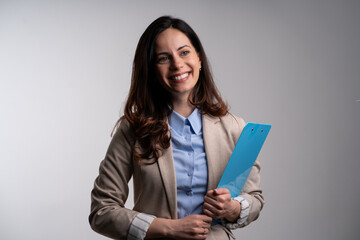 Fototapeta premium Photo of gorgeous brunette secretary woman with long curly hair writing down notes in clipboard while working in office