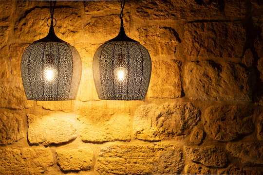 Ornate metal pendant lamps illuminating stone wall
