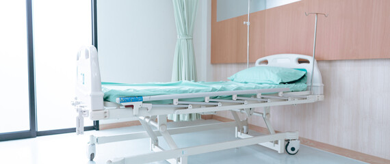 A hospital room shows an empty bed ready for a patient. The bed has light blue sheets and there are...