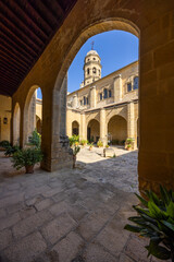 Fototapeta premium Baeza cathedral cloister archway framing bell tower under blue sky
