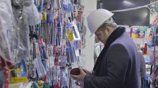 Man in a hard hat inspecting goods in a hardware store