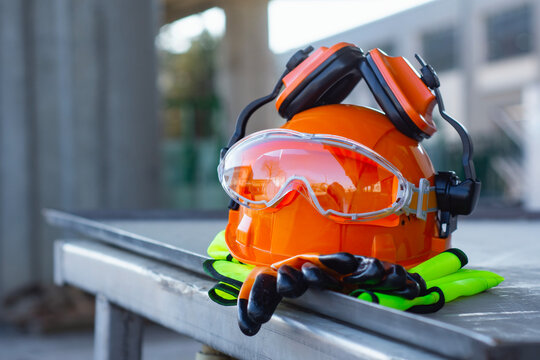 Construction safety helmet with protective goggles, gloves and reflective vest on industrial site. Concept of workplace safety, protective equipment, construction industry and labor protection.