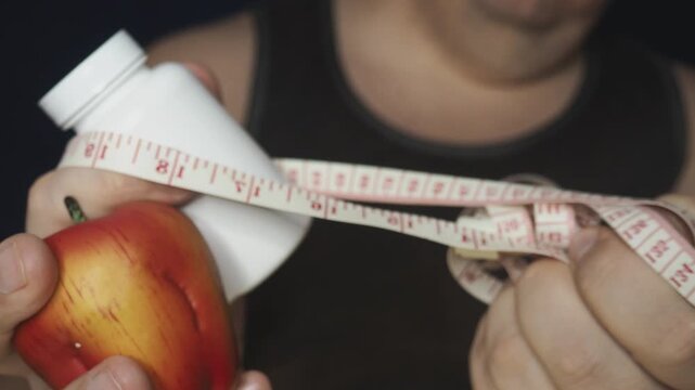 Overweight or obese man with abdominal fat using a tape measure to check his waist size