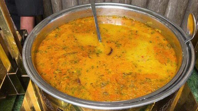 Yellow-coloured Masoor dal served in an Indian wedding