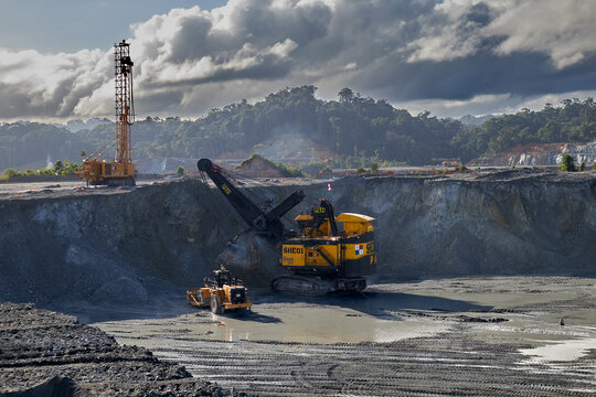 Large electric rope shovel loading haul trucks in an open-pit mining operation, demonstrating high-efficiency material handling under strict safety protocols and coordinated traffic control. 
