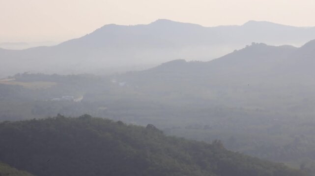Natural video background of a high-angle atmosphere on a mountain that overlooks the surrounding scenery(mountains, trees,sea)from a scenic vantage point,with a wooden chair for sitting and resting