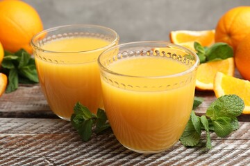 Citrus juice in glasses, fresh oranges and mint leaves on wooden table, closeup © New Africa