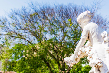 Obraz premium Female sculpture superimposed on a background filled with blurred trees.Sunlight highlights the marble,creating a vibrant contrast with the landscape.Artist unknown, São João Batista Cemetery, Brazil 