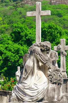 Female sculpture leaning on a cross, in a gesture of dejection and surrender. The scene expresses mourning and emotional exhaustion in the face of death. Artist unknown, S&atilde;o Jo&atilde;o Batista Cemetery, RJ.