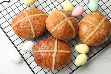 Hot cross buns and decorated eggs on white table, flat lay