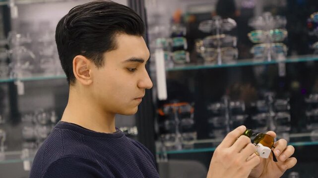 Young man trying on glasses and smiling in an optics store