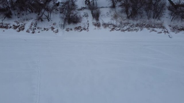 Aerial view of snow-covered houses near frozen river in Uralsk, Kazakhstan, during winter. c.