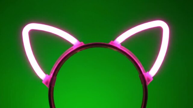 Glowing pink cat ear headbands flash in sequence against a vibrant green background