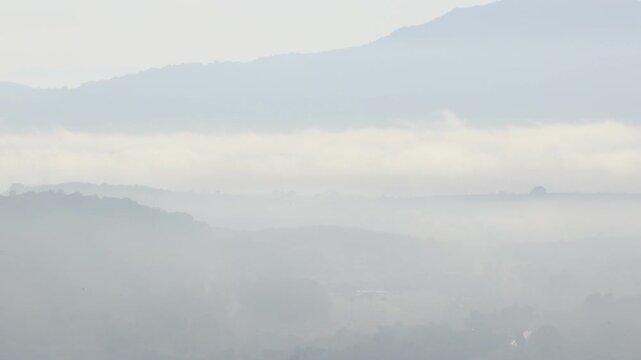 Natural video background of a high-angle atmosphere on a mountain that overlooks the surrounding scenery(mountains, trees,sea)from a scenic vantage point,with a wooden chair for sitting and resting