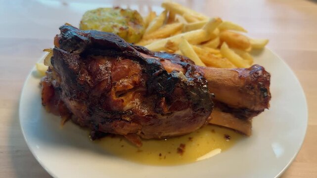 Pork knuckle served with crispy French fries on the table, tender, smoky, and packed with taste. High quality 4k footage