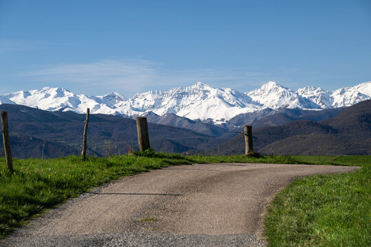 Country road in the mountains with snow-capped peaks in the background Ariege Pyrenees France