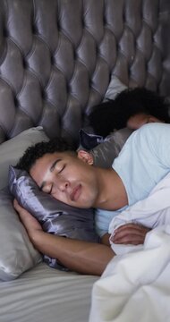 Vertical video: Lying man wearing blue T-shirt breathing softly on satin pillow, soft light lulling