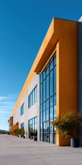 Naklejka premium Modern glass commercial building orange corner exterior with potted plants under clear blue sky urban architecture facade