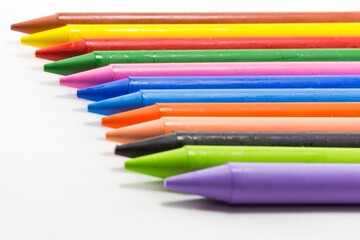 Fototapeta premium Colorful Wax Crayons Arranged in a Row on White Background