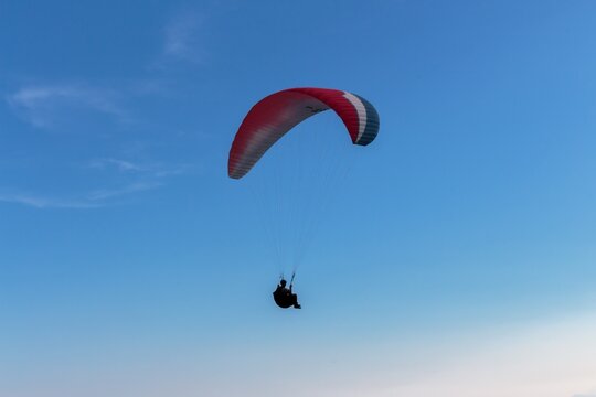 Paraglider Silhouette Flying Against Clear Blue Sky