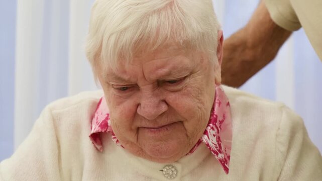 Elderly woman with white hair sitting at a table and concentrating on completing a jigsaw puzzle, showcasing a hobby that stimulates cognitive function and provides enjoyment