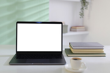 Fototapeta premium Stylish workplace with laptop, notepads and cup of coffee on white desk indoors, closeup