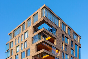 Obraz premium A detailed architectural photograph of a modern brick residential building corner against a clear blue sky.