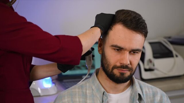 Trichologist examining man's hair and scalp with dermatoscope