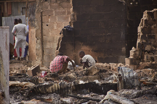 Kano, Nigeria - 27 January 2024: View of the charred remains of a building where a child plays amidst the debris, the somber scene framed by the partially collapsed brickwork.